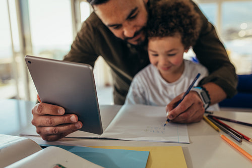 Man teaching his kid using a digital tablet
