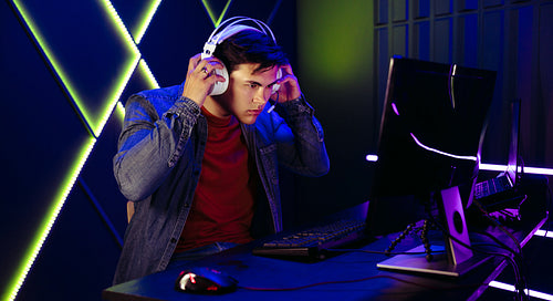 Young male gamer immersing himself in a pc gaming session with a headset