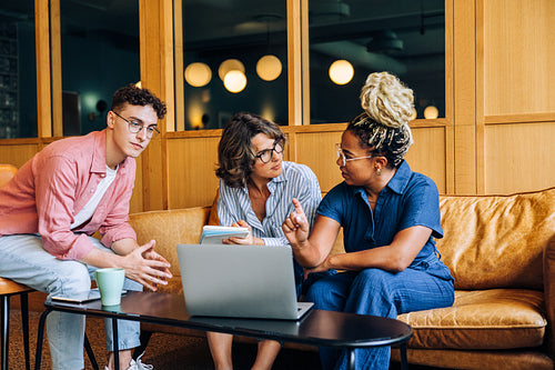 Group of three colleagues discussing ideas in a modern office setting