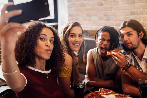 Diverse group of friends enjoying meal and taking selfie 