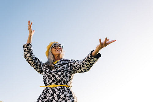 Carefree elderly woman lifting her hands in celebration outdoors