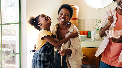 Brazilian girl and her mother laughing while baking as a family in the kitchen