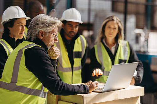 Warehouse manager showing his staff a slideshow presentation on a laptop