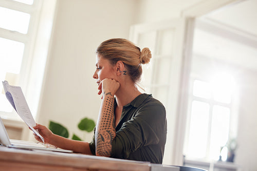 Woman going through contract papers at home office