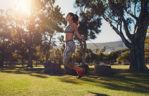 Fit young woman skipping with a jump rope in the park 