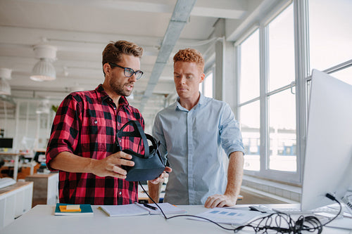 Young men testing virtual reality goggles in office