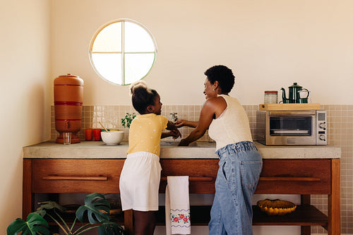 Brazilian mother and daughter cleaning their hands with clay filer water