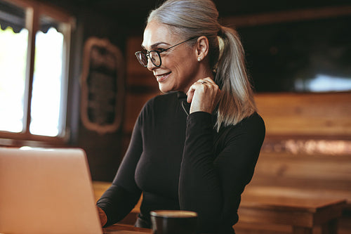 Beautiful senior woman at cafe using laptop computer