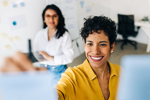 Creative business women writing ideas on sticky notes in an office