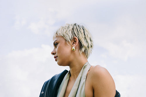 Blonde woman poses in profile against a bright sky