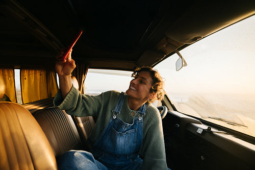 A woman in overalls takes a selfie inside a sunlit van