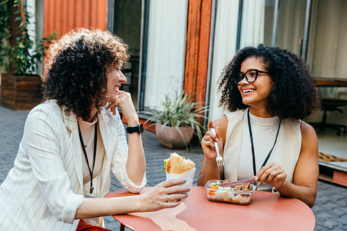 Female colleagues enjoying a lunch break in the office courtyard, sharing smiles and conversation during a relaxing midday pause