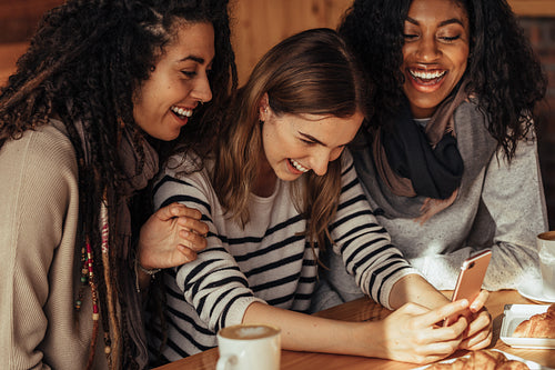 Friends at a cafe looking at mobile phone