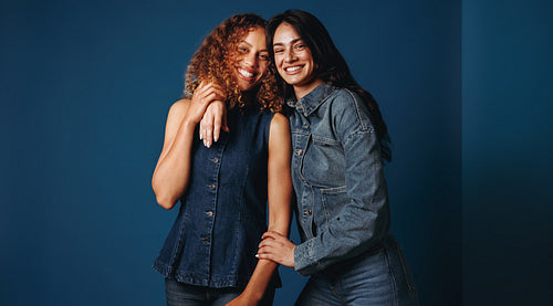 Smiling women friends pose together in a studio portrait with confidence