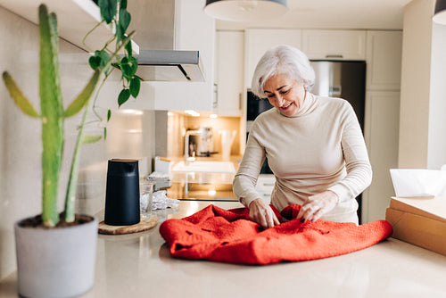 Mature online shopper unpacking a clothing delivery at home