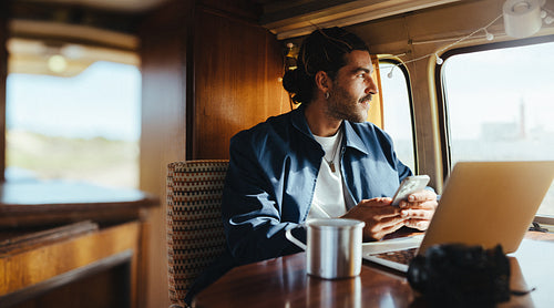 Taking a moment: Man looks out the camper window while holding his phone