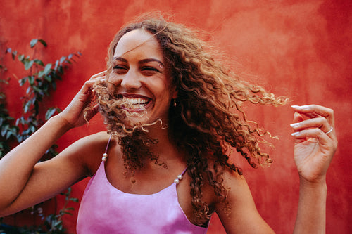 Joyful woman with curly hair laughs in the wind outdoors