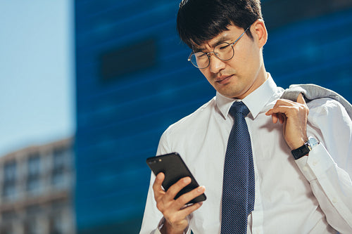 Businessman reading text message on his mobile phone outdoors