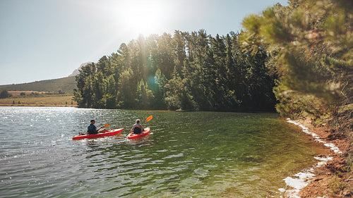 Kayakers rowing together on still lake