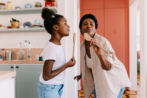 Mother and daughter singing together in the kitchen at home