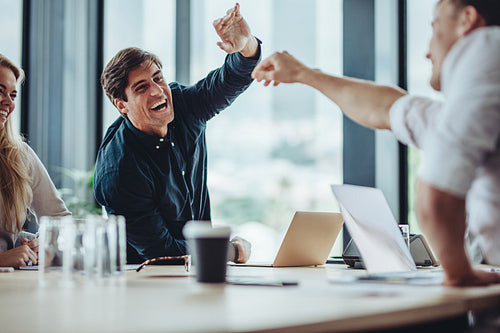 Businesspeople excitedly high fiving together in meeting
