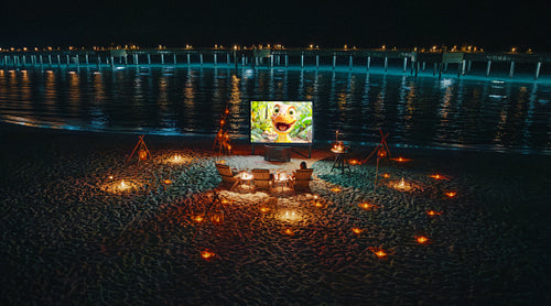 Luxury night movie experience on the seashore with cozy seating and ambient lanterns