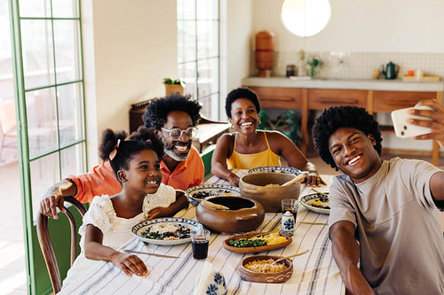 Brazilian family taking a selfie at the dining table, serving traditional food