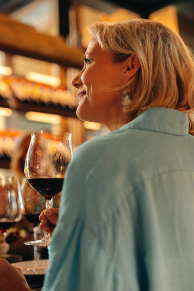 Smiling woman enjoying wine tasting experience in a bright and happy shop