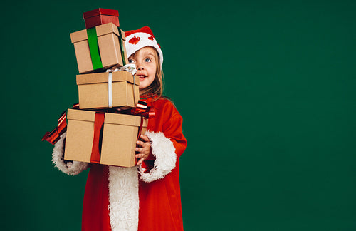 Kid in santa costume holding gift boxes