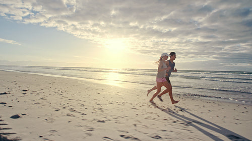 Couple running along the beach in morning