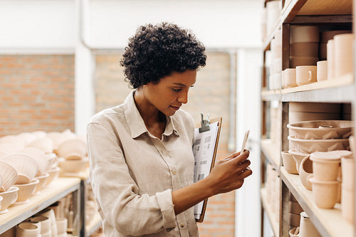 Female ceramic store owner taking a picture of her earthenware products