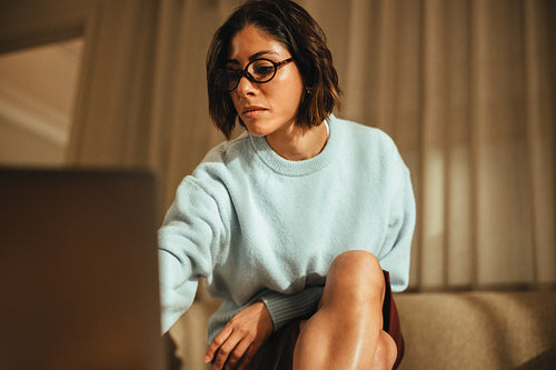 Focused businesswoman works on laptop in office with natural lighting