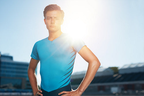 Confident male athlete standing in stadium