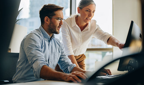 Businessman and woman working on computer together