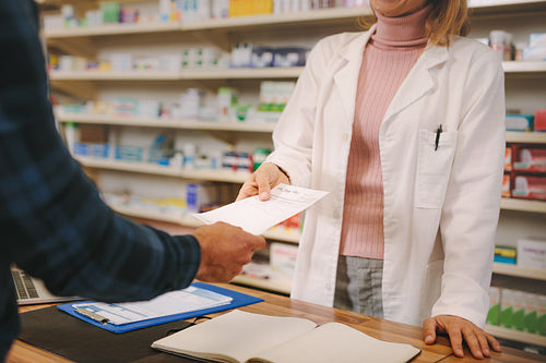 Customer handing over a prescription to the chemist 