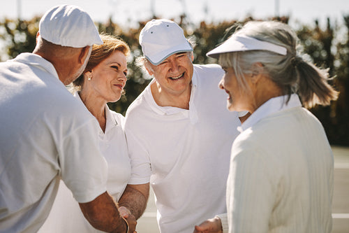 Senior men and women shaking hands after the tennis match