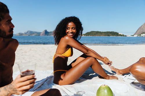 Young woman relaxing on a picnic blanket and enjoying a day with friends at the beach