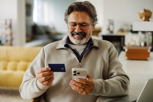 Senior man shops online with credit card at home