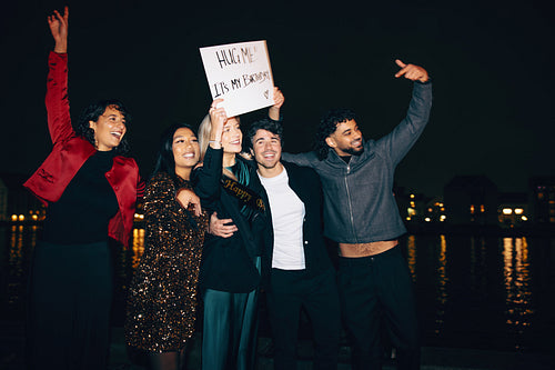 Group celebrating a birthday outdoors at night near the water