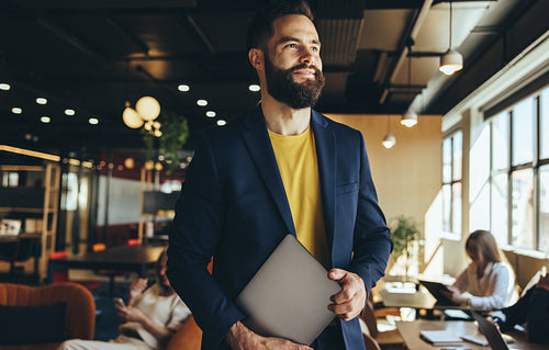 Thoughtful businessman standing in a co-working space