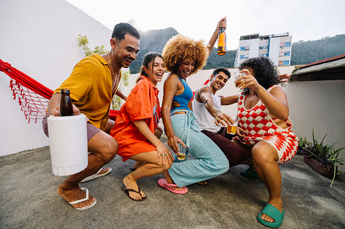 Brazilian friends dancing funk and sharing drinks on a rooftop in Rio