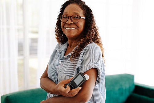 Senior woman using a flash glucose monitor to manage her diabetes at home
