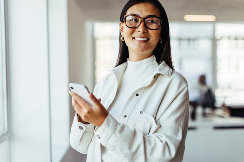 Thoughtful business woman holding a mobile phone in her workplace