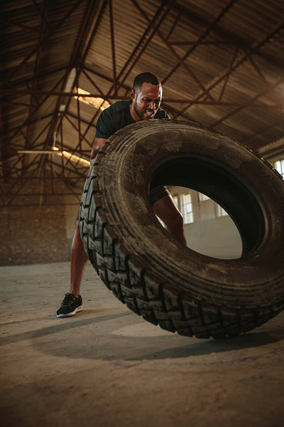 Man doing tire flipping workout at empty warehouse