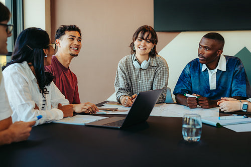 Diverse group of classmates working together around a table engaged in a collaborative discussion, sharing ideas and studying