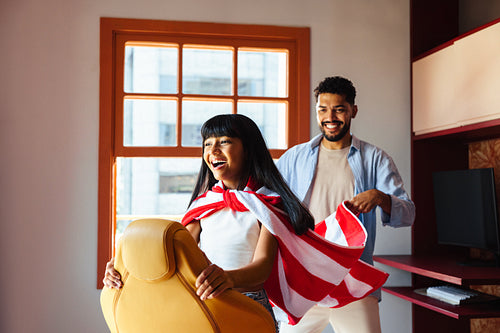 Father and daughter playing together with a striped cape indoors