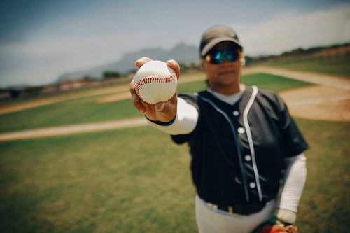 Baseball pitcher holding ball ready to play on the field in a bright sunny day