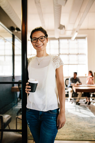 Relaxed woman in office doorway with coffee