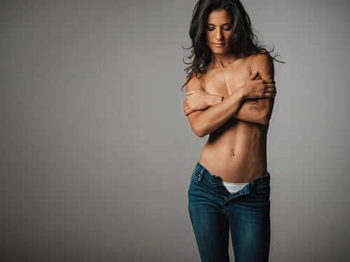 Topless woman looks down as she crosses her arms