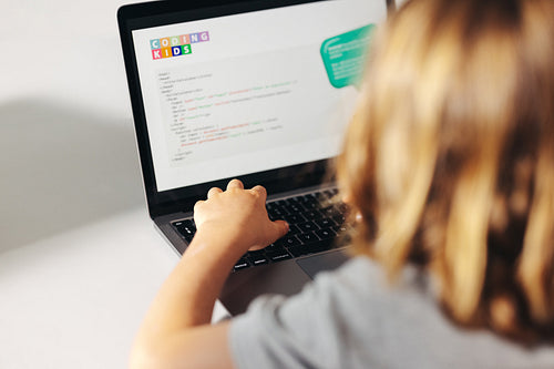 Young coding prodigy in action: Child programming on a laptop in a classroom